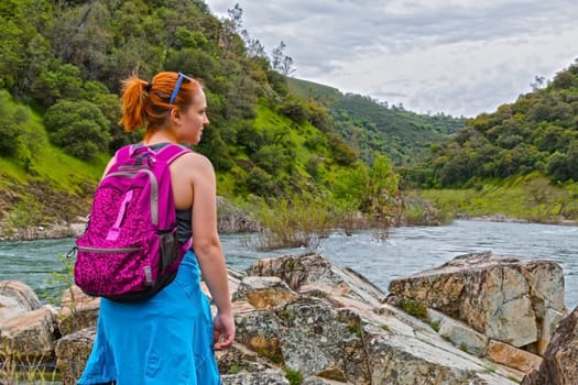 Young Girl Standing on Rocks Near Fast River