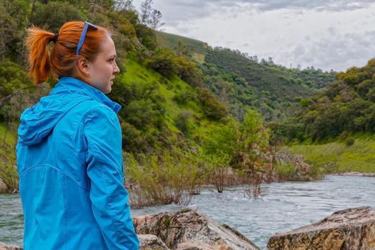 Young Girl Standing on Rocks Near Fast River