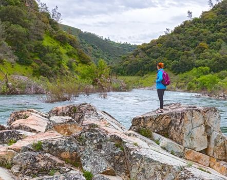 Young Girl Standing on Rocks Near Fast River