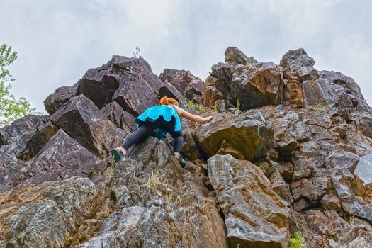 Young Girl Climbing up Rocks and Reaching for Another Rock