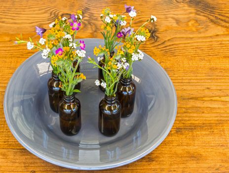 Gray Plate With Small Vases With Flowers Sitting on Wooden Table