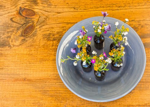 Gray Plate With Small Vases With Flowers Sitting on Wooden Table
