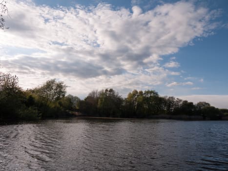 sunset over a lake in spring with moving waves ripples and clouds with trees around water in spring beauty clear and serene and beautiful