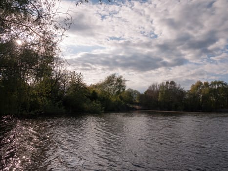 sunset over a lake in spring with moving waves ripples and clouds with trees around water in spring beauty lovely day