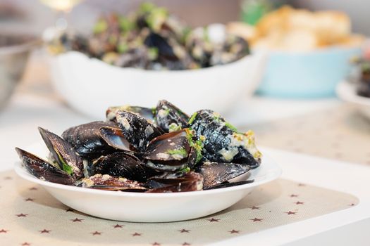 Steamed mussels in cheese sauce. Mussels in shells in the bowl with white wine on the table.