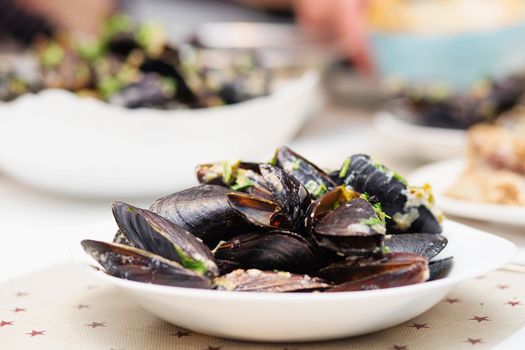 Steamed mussels in cheese sauce. Mussels in shells in the bowl with white wine on the table.