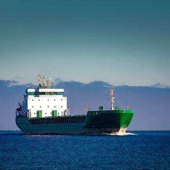 Green cargo ship moving in still water of Baltic sea