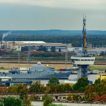 Military ship sailing past the cargo port in Riga, Latvia