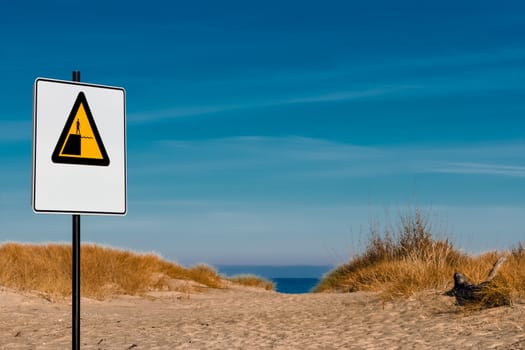 Yellow warning sign on summer beach, Riga