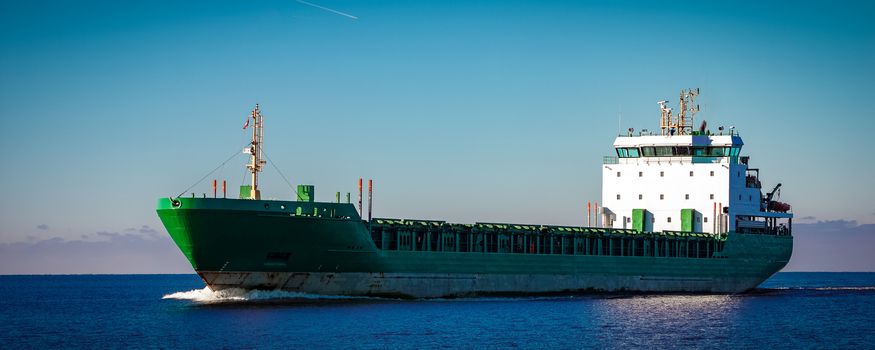 Green cargo ship moving in still water of Baltic sea