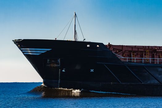 Black cargo ship's bow. Bulk carrier sailing in still Baltic sea