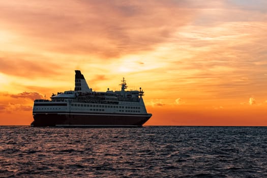 Cruise liner in open sea. Passenger ferry sailing at hot sunset