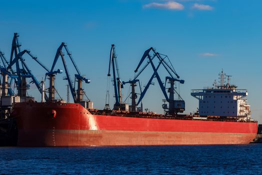 Red cargo ship loading in the port of Riga, Europe