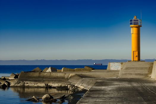 Yellow lighthouse on breakwater dam in Riga, Europe