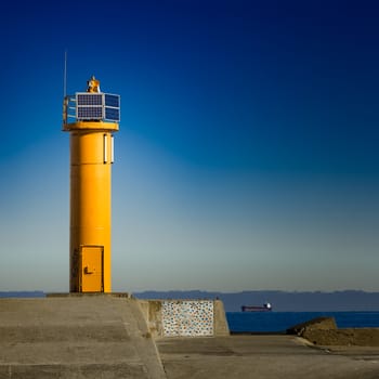 Yellow lighthouse on breakwater dam in Riga, Europe