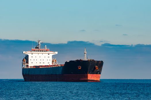 Black cargo ship moving in still Baltic sea water. Riga, Europe