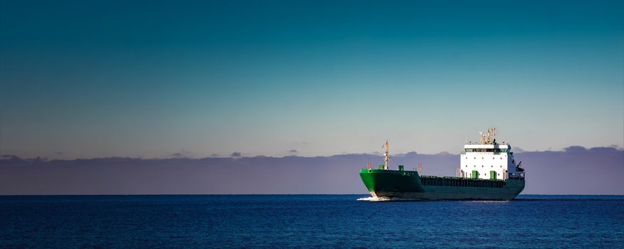 Green cargo ship moving in still water of Baltic sea