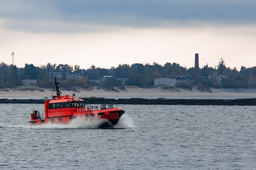 Red pilot ship moving at speed to Baltic sea in Riga, Europe