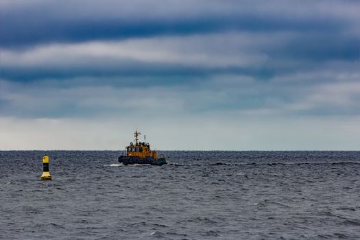 Small orange tug ship moving from the Baltic sea