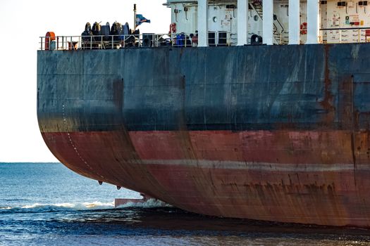 Black cargo ship's stern in still water close up. Riga, Europe