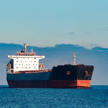 Black cargo ship moving in still Baltic sea water. Riga, Europe