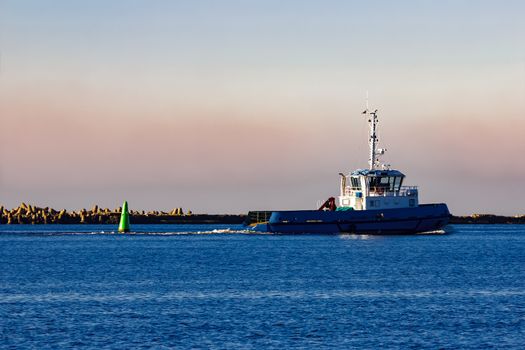 Blue small tug ship leaving Riga and entering the Baltic sea