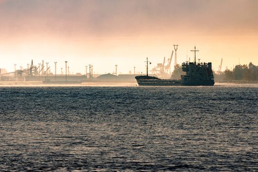 Cargo ship silhouette entering a port of Riga at the morning