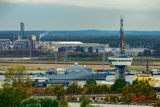 Military ship sailing past the cargo port in Riga, Latvia