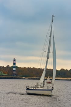 White sailboat traveling past the lighthouse in Riga