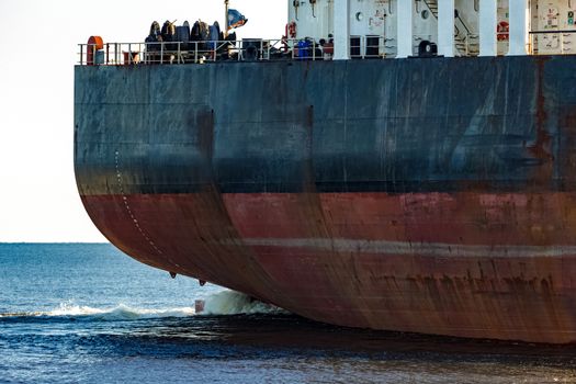 Black cargo ship's stern in still water close up. Riga, Europe