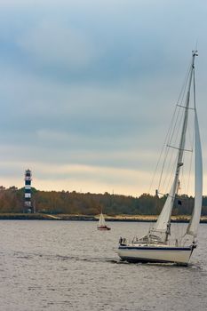 White sailboat traveling past the lighthouse in Riga