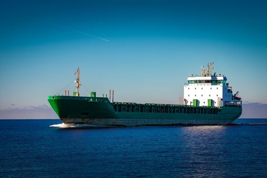 Green cargo ship moving in still water of Baltic sea