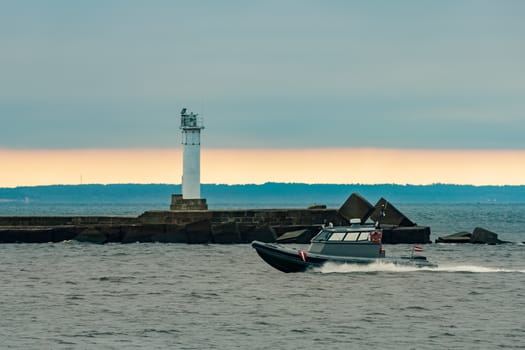 Small grey border guard boat moving fast in still evening