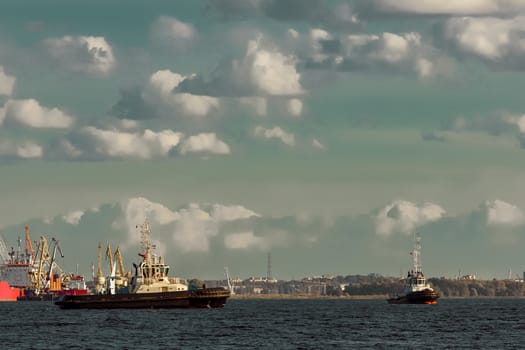 Two tug ships are accepting cargo vessel at Daugava river