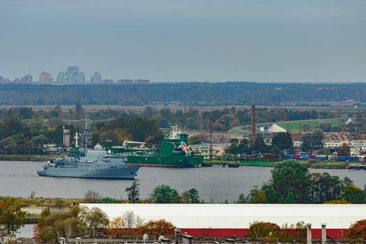 Military ship sailing past the cargo port in Riga, Latvia