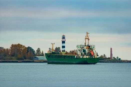 Green cargo ship moving to the port in cloudy day