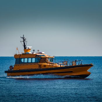 Yellow pilot ship moving at speed from the Baltic sea