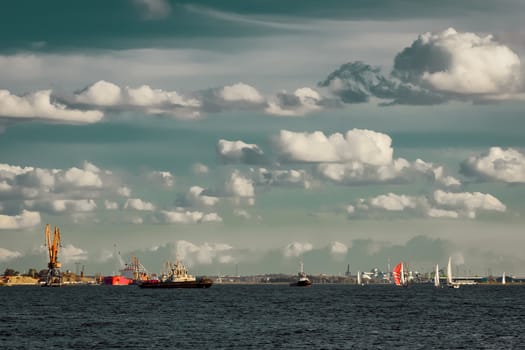 Tug ships and sailboats against cargo terminal in Riga