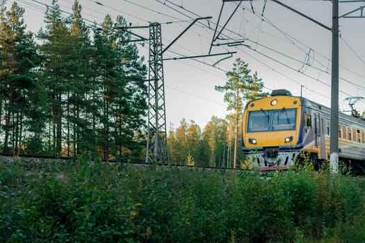 Passenger electric train moving through forest in Riga