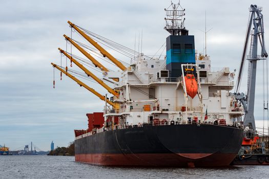 Black cargo ship loading in the port of Riga, Europe