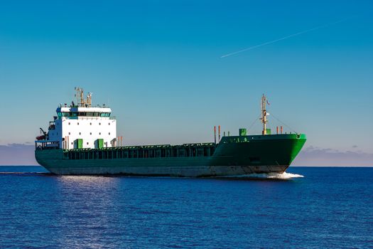 Green cargo ship moving in still water of Baltic sea