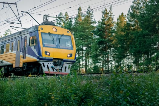 Passenger electric train moving through forest in Riga