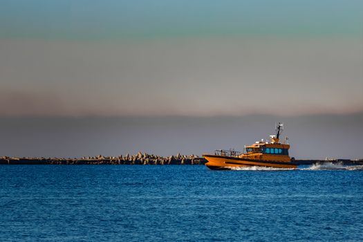 Orange pilot ship sailing from the Baltic sea in Latvia