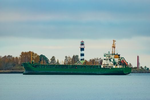 Green cargo ship moving to the port in cloudy day