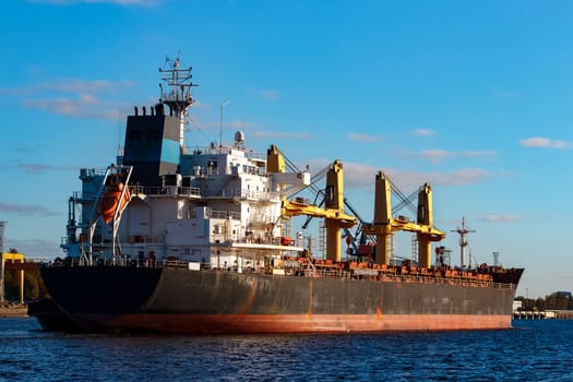 Black cargo ship entering the port of Riga, Europe