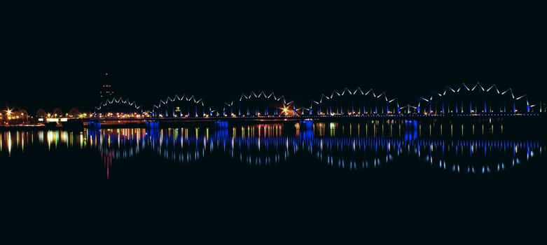 Illuminated railroad bridge in night city, Latvia. Riga bridge