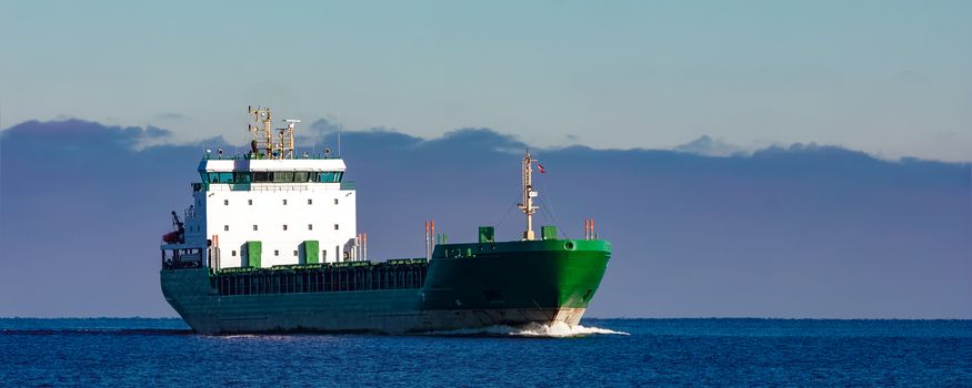 Green cargo ship moving in still water of Baltic sea