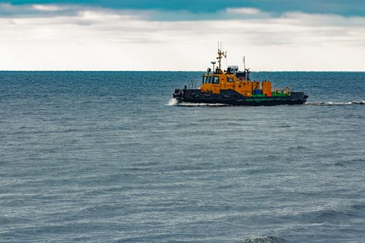 Small orange tug ship moving from the Baltic sea