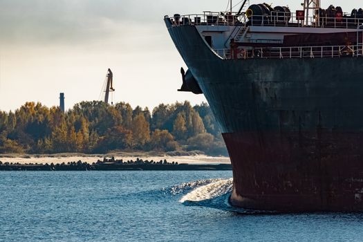 Black cargo ship's bow entering Riga, Europe