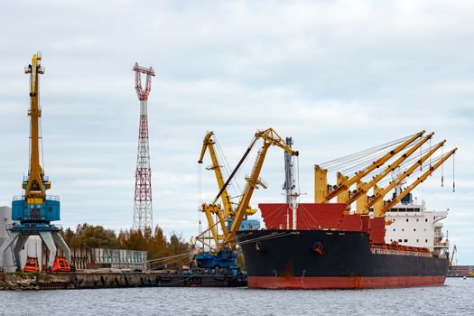 Black cargo ship loading in the port of Riga, Europe